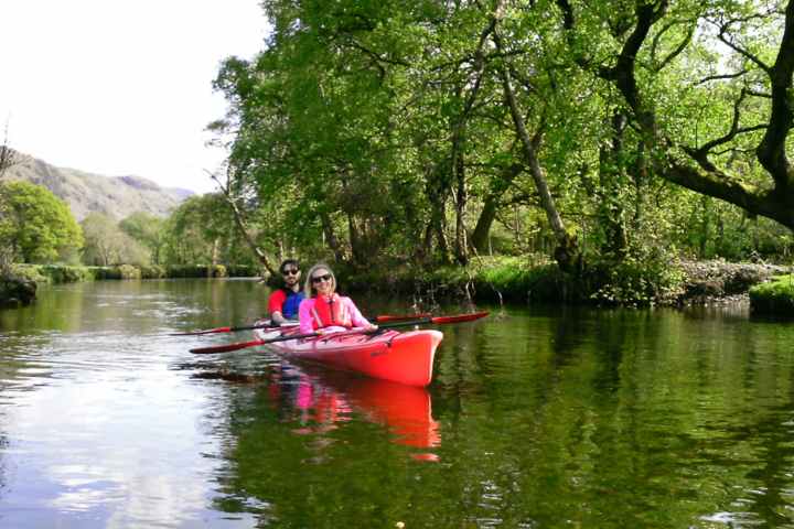 A couple enjoying a guided kayak tour on Ullswater in The Lake District.