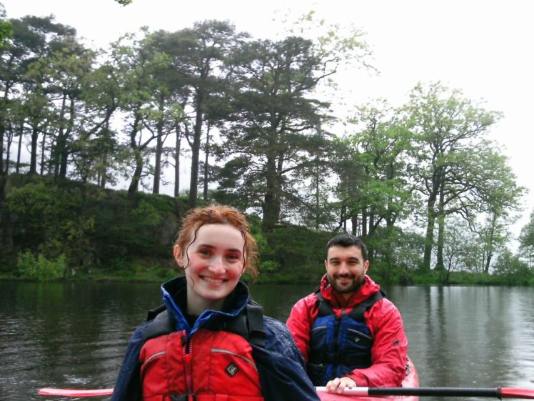 A young couple paddling a kayak on the beautiful waters of Ullswater, surrounded by the gorgeous scenery of The Lake District.