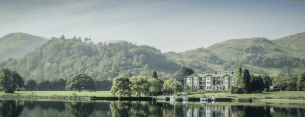 The Inn on the Lake, a charming lakeside hotel with traditional architecture, set against the backdrop of a tranquil lake and scenic hills