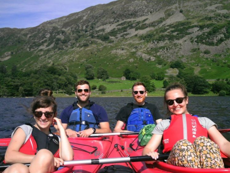 Two couples enjoying an outdoor adventure in the scenic Lake District, surrounded by lush greenery and breathtaking lake views