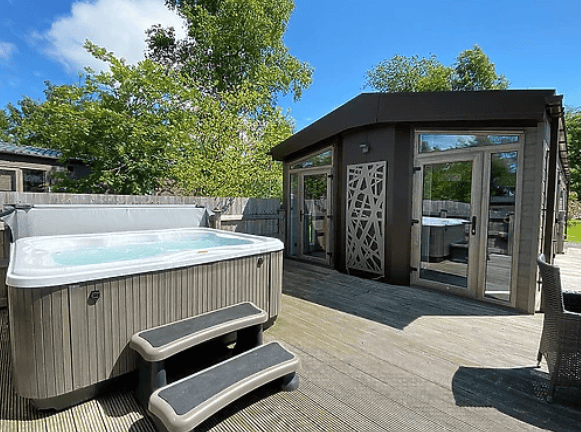 Luxurious lodge at Flusco Wood featuring a private outdoor hot tub on a spacious deck, nestled amidst the serene landscapes of the Lake District